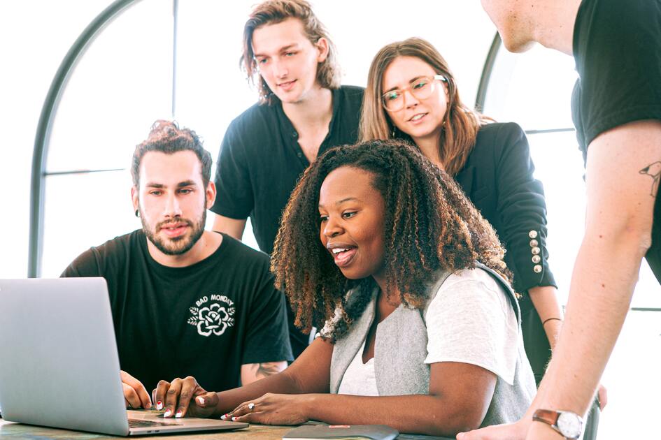 Marketing team huddling in front of a computer