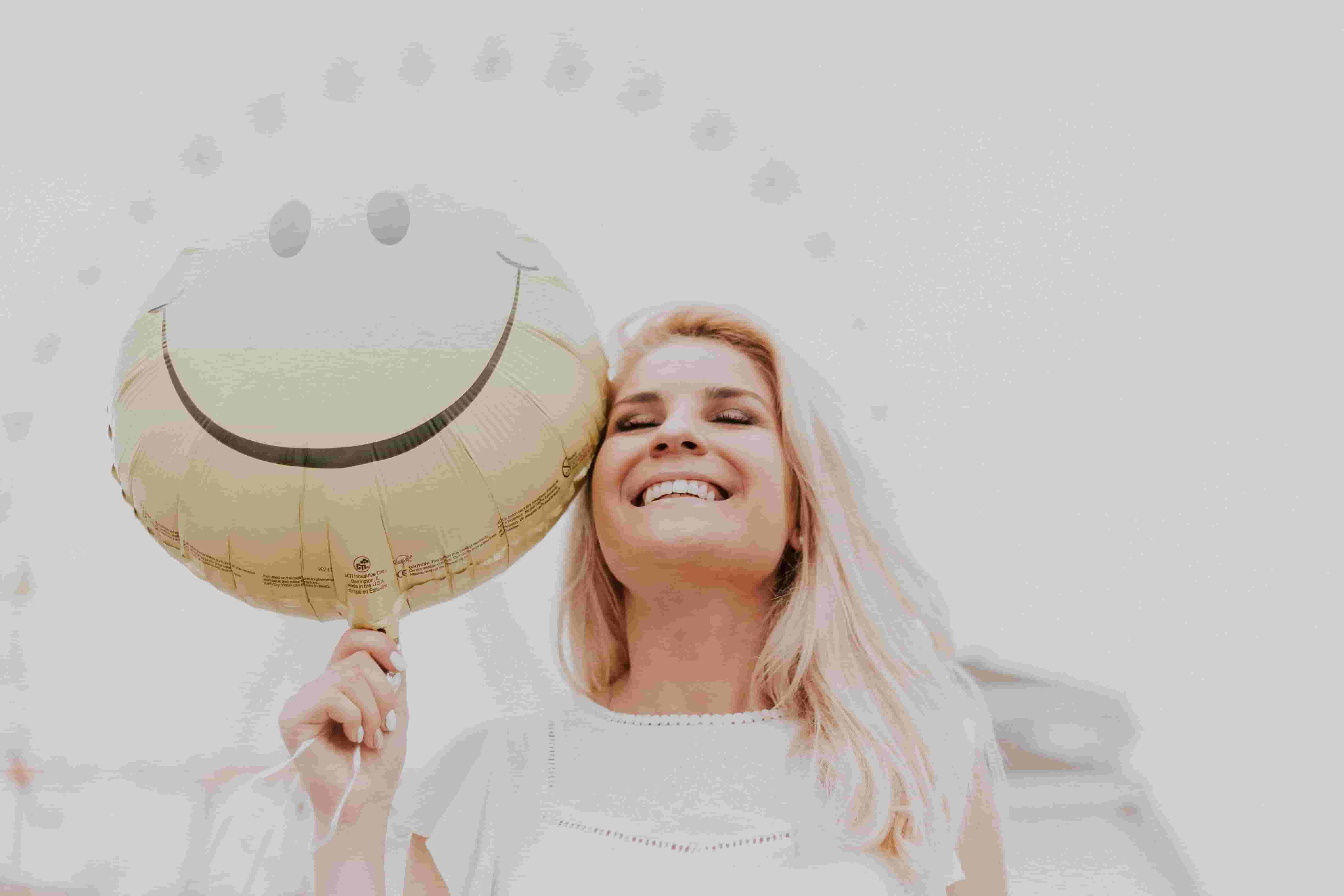 woman happily holding a smiley balloon